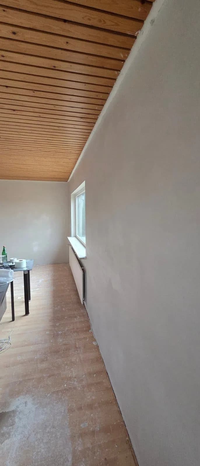 Strak afgewerkte wand onder een houten schrootjesplafond